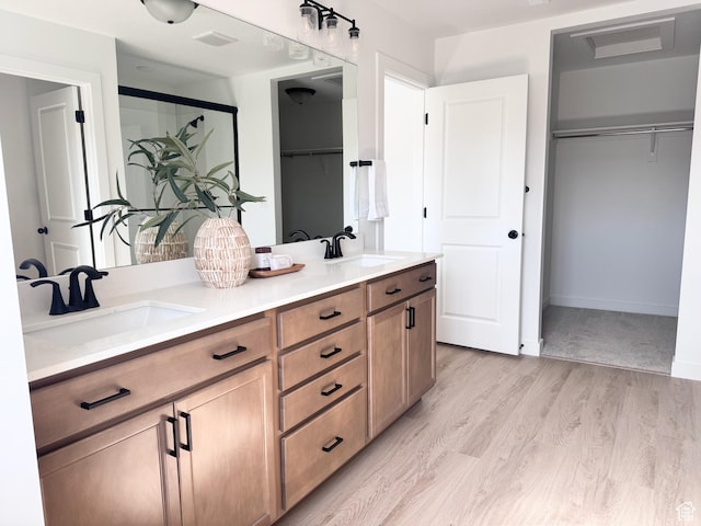 189 N Woodrun Way Unit 131, Saratoga Springs, UT 84045 - full bathroom featuring a walk in closet, double vanity, wood finished floors, and a shower with shower door