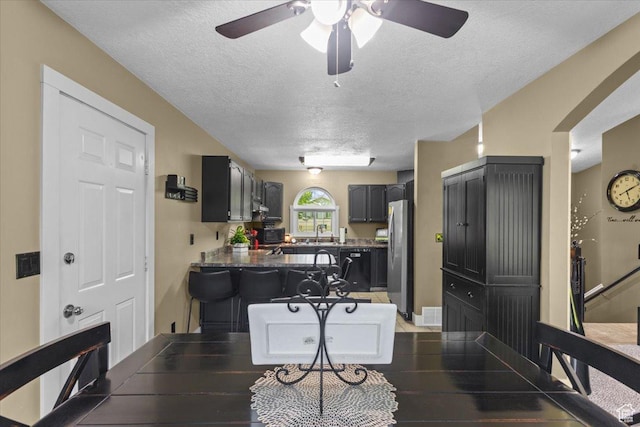 980 E 2850 N, North Logan, UT 84341 - kitchen with freestanding refrigerator, a textured ceiling, ceiling fan, a peninsula, and dark countertops