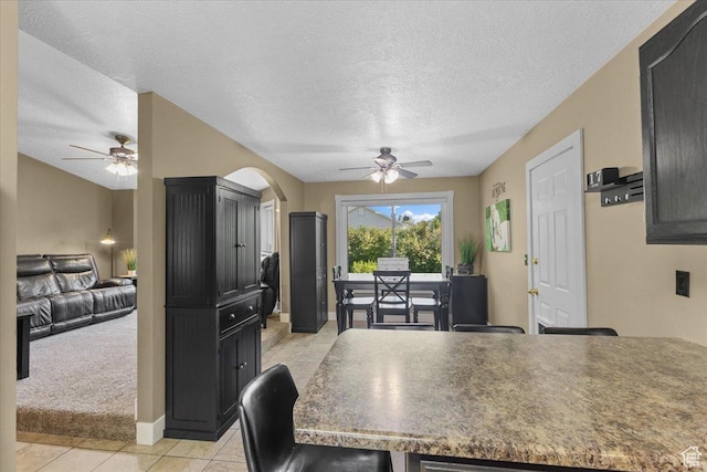 980 E 2850 N, North Logan, UT 84341 - dining space with a ceiling fan, light tile patterned flooring, a textured ceiling, light colored carpet, and arched walkways