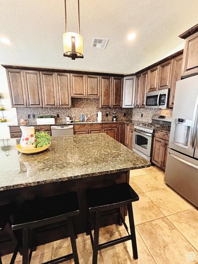 3853 Mitchell Dr, Santa Clara, UT 84765 - kitchen featuring stainless steel appliances, a kitchen breakfast bar, backsplash, dark stone counters, and a textured ceiling