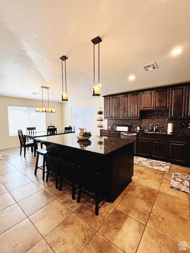 3853 Mitchell Dr, Santa Clara, UT 84765 - kitchen with backsplash, a textured ceiling, a breakfast bar area, pendant lighting, and dark countertops