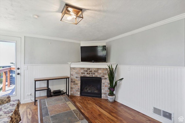 2077 Fillmore Ave, Ogden, UT 84401 - living room with wood finished floors, a textured ceiling, a wainscoted wall, a fireplace, and crown molding