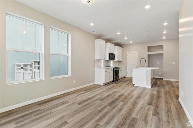 6168 W Franciscotti Dr Unit 605, South Jordan, UT 84009 - kitchen with stainless steel electric stove, light wood finished floors, a kitchen island with sink, white cabinets, and recessed lighting