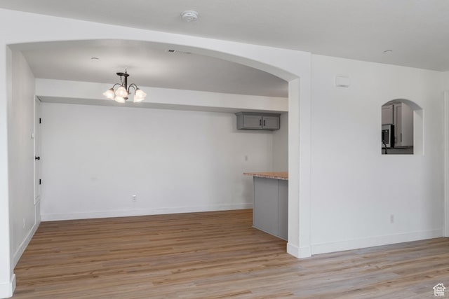 3812 E Rock Creek Rd Unit 5, Eagle Mountain, UT 84005 - unfurnished dining area with light wood-style flooring, a chandelier, and arched walkways