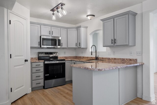 3812 E Rock Creek Rd Unit 5, Eagle Mountain, UT 84005 - kitchen featuring appliances with stainless steel finishes, gray cabinetry, light wood finished floors, arched walkways, and a peninsula