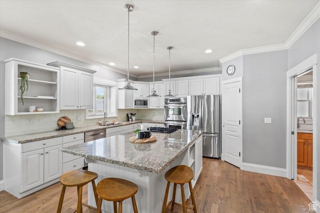 6264 S Dellron Dr, Murray, UT 84123 - kitchen with appliances with stainless steel finishes, a breakfast bar area, white cabinets, a kitchen island, and crown molding