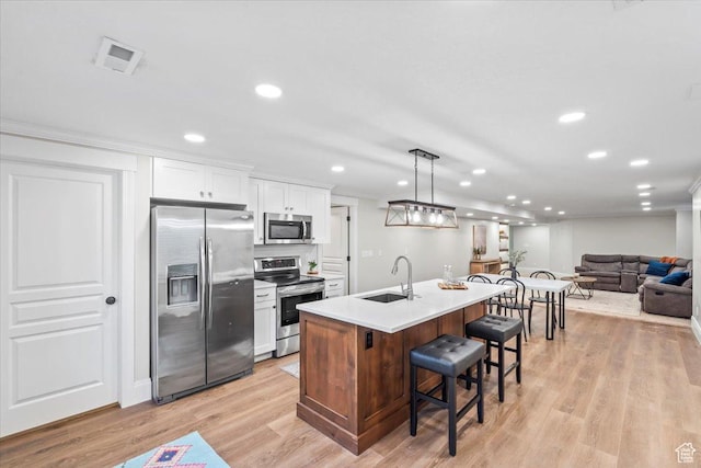 6264 S Dellron Dr, Murray, UT 84123 - kitchen with stainless steel appliances, a breakfast bar area, white cabinetry, an island with sink, and recessed lighting