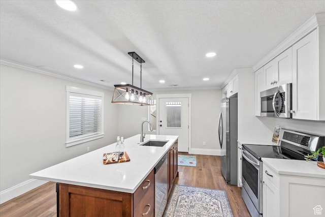 6264 S Dellron Dr, Murray, UT 84123 - kitchen with stainless steel appliances, an island with sink, crown molding, light countertops, and wood finished floors