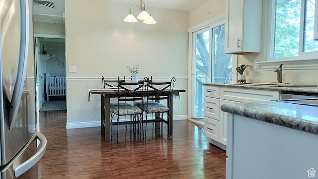 5373 W 6600 S, West Jordan, UT 84081 - dining space with wainscoting, dark wood-style flooring, a chandelier, and healthy amount of natural light