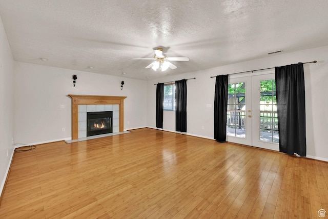 4188 S 2725 W, Roy, UT 84067 - unfurnished living room with a ceiling fan, a textured ceiling, a tile fireplace, light wood-style flooring, and french doors