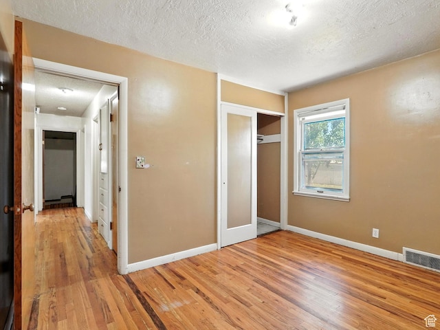 1951 W 4900 S, Roy, UT 84067 - unfurnished bedroom with a textured ceiling, light wood-style flooring, and a closet