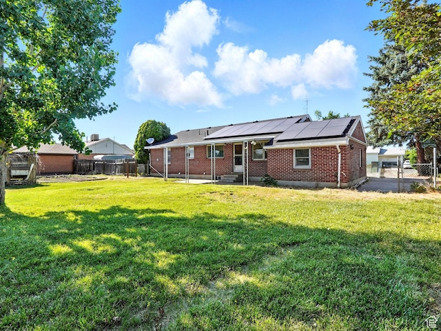 1951 W 4900 S, Roy, UT 84067 - back of property with roof mounted solar panels, a fenced backyard, brick siding, and a patio area