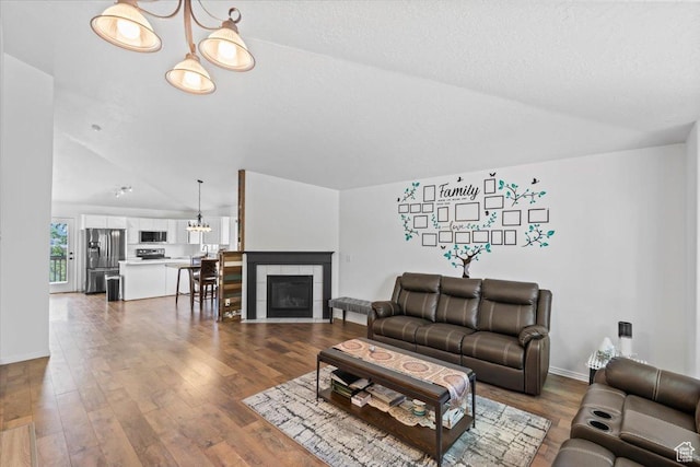 3186 N 1175 E, Layton, UT 84040 - living room with lofted ceiling, wood finished floors, a tiled fireplace, and a chandelier