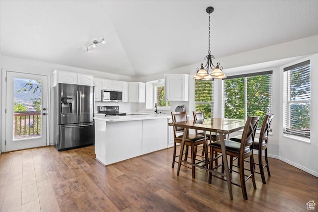 3186 N 1175 E, Layton, UT 84040 - kitchen featuring stainless steel appliances, white cabinetry, lofted ceiling, wood finished floors, and a chandelier
