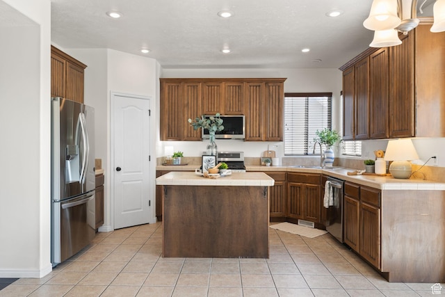 3991 W Hollandia Ln, West Jordan, UT 84084 - kitchen featuring appliances with stainless steel finishes, a center island, light tile patterned floors, recessed lighting, and tile countertops