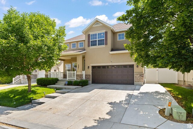 3991 W Hollandia Ln, West Jordan, UT 84084 - view of front of house with stone siding, stucco siding, an attached garage, concrete driveway, and a gate