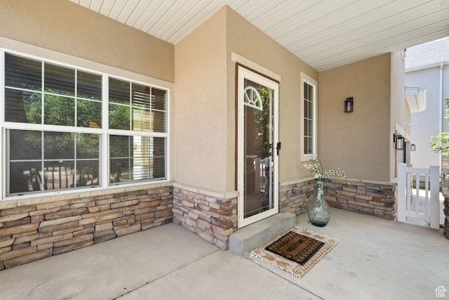 3991 W Hollandia Ln, West Jordan, UT 84084 - view of exterior entry with stone siding, stucco siding, and covered porch