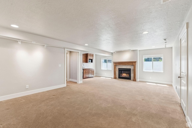 11103 S Kiwano Way W, South Jordan, UT 84009 - unfurnished living room with light carpet, a textured ceiling, a tiled fireplace, healthy amount of natural light, and recessed lighting