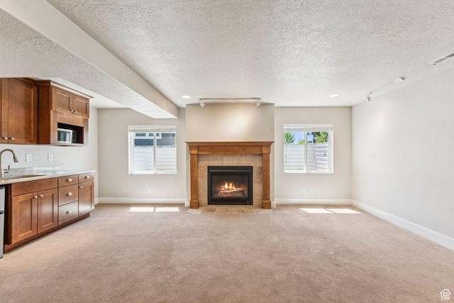 11103 S Kiwano Way W, South Jordan, UT 84009 - unfurnished living room featuring a tile fireplace, light carpet, a textured ceiling, and track lighting
