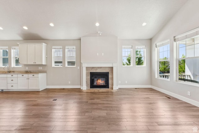 11103 S Kiwano Way W, South Jordan, UT 84009 - unfurnished living room featuring light wood finished floors, recessed lighting, a tile fireplace, and a textured ceiling