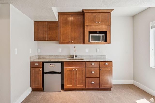 11103 S Kiwano Way W, South Jordan, UT 84009 - kitchen with freestanding refrigerator, light carpet, brown cabinetry, light stone counters, and a textured ceiling