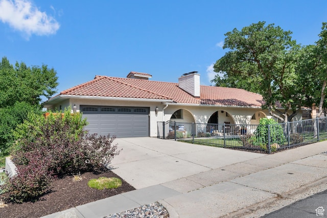 7968 S Titian St E, Cottonwood Heights, UT 84121 - mediterranean / spanish-style house featuring a tile roof, a chimney, an attached garage, driveway, and stucco siding