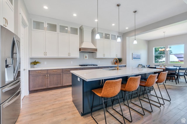 586 S Appenzell Ln W Unit 16, Midway, UT 84049 - kitchen with stainless steel refrigerator with ice dispenser, premium range hood, light wood finished floors, white cabinets, and a kitchen breakfast bar
