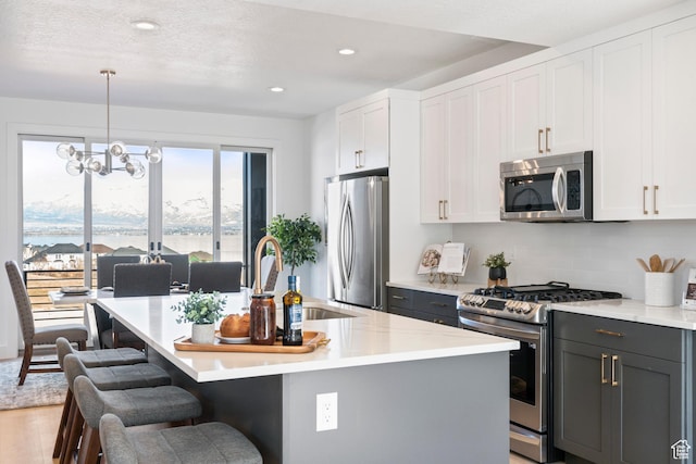 79 E Watson Dr, Saratoga Springs, UT 84045 - kitchen with appliances with stainless steel finishes, an island with sink, a kitchen breakfast bar, recessed lighting, and tasteful backsplash