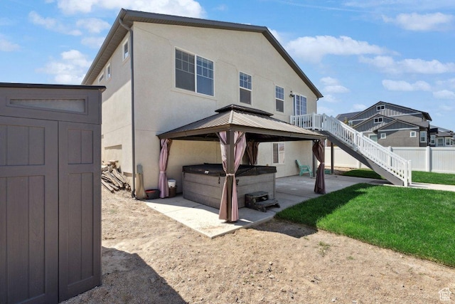 6228 N Boulter Peak Ln, Eagle Mountain, UT 84005 - back of house featuring a hot tub, a patio area, a gazebo, stucco siding, and a shed