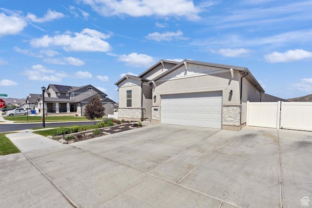 6228 N Boulter Peak Ln, Eagle Mountain, UT 84005 - view of front facade featuring a garage, driveway, stone siding, stucco siding, and a gate