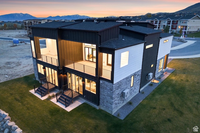 78 Watson Dr, Saratoga Springs, UT 84045 - back of property at dusk featuring roof with shingles, a mountain view, a balcony, and a yard