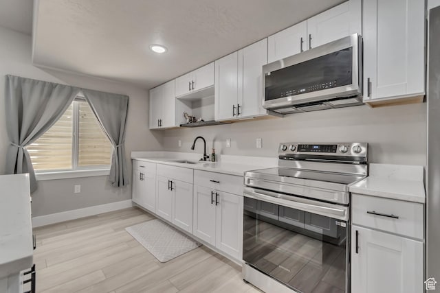 992 W Emily Francis Cir S, Jordan, UT 84095 - kitchen featuring stainless steel appliances, light countertops, white cabinets, open shelves, and light wood-style floors