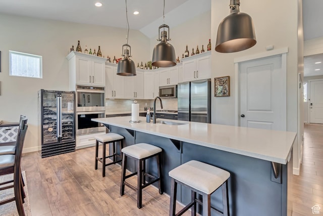 992 W Emily Francis Cir S, Jordan, UT 84095 - kitchen with appliances with stainless steel finishes, light wood-style flooring, high vaulted ceiling, light countertops, and beverage cooler