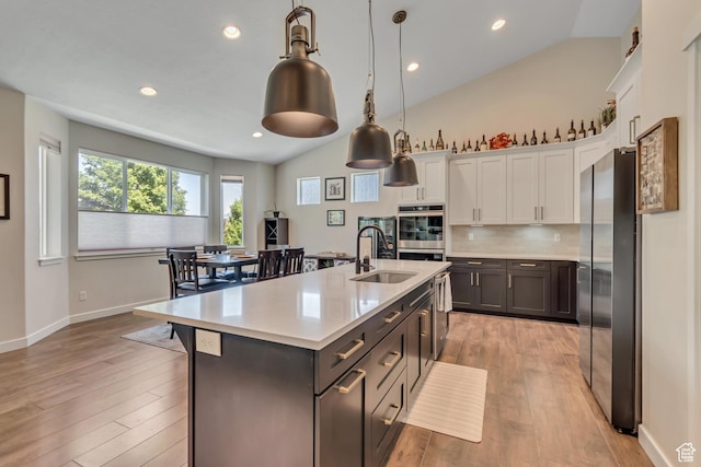 992 W Emily Francis Cir S, Jordan, UT 84095 - kitchen featuring stainless steel appliances, white cabinets, light countertops, lofted ceiling, and light wood-style floors