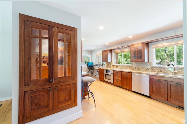 1983 E 1700 S, Salt Lake City, UT 84108 - kitchen featuring stainless steel appliances, brown cabinets, light wood finished floors, tasteful backsplash, and glass insert cabinets