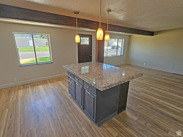 10138 S Peony Way, Sandy, UT 84094 - kitchen with a textured ceiling, wood finished floors, open floor plan, a kitchen island, and light stone countertops