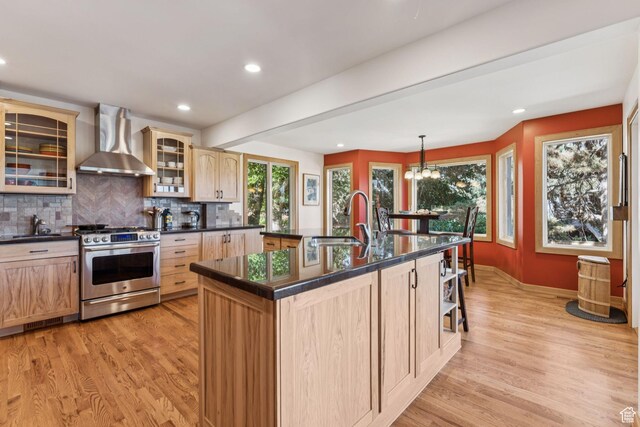 4714 S Idlewild Rd, Millcreek, UT 84124 - kitchen featuring wall chimney exhaust hood, gas range, light brown cabinetry, dark countertops, and light wood-style flooring