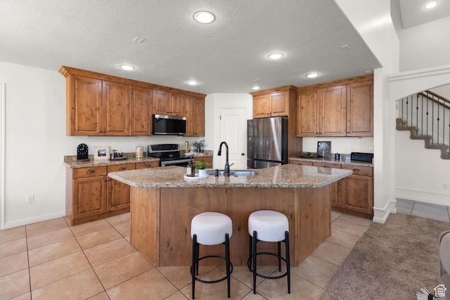 15337 S Eagle Crest Dr E, Draper, UT 84020 - kitchen with stainless steel appliances, brown cabinetry, light tile patterned flooring, an island with sink, and recessed lighting