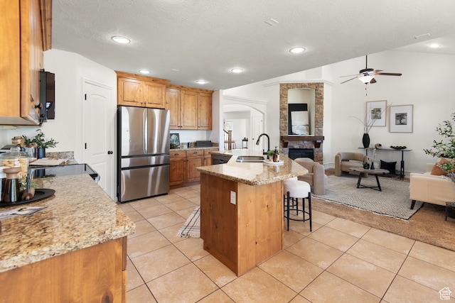 15337 S Eagle Crest Dr E, Draper, UT 84020 - kitchen featuring freestanding refrigerator, open floor plan, ceiling fan, a kitchen bar, and arched walkways