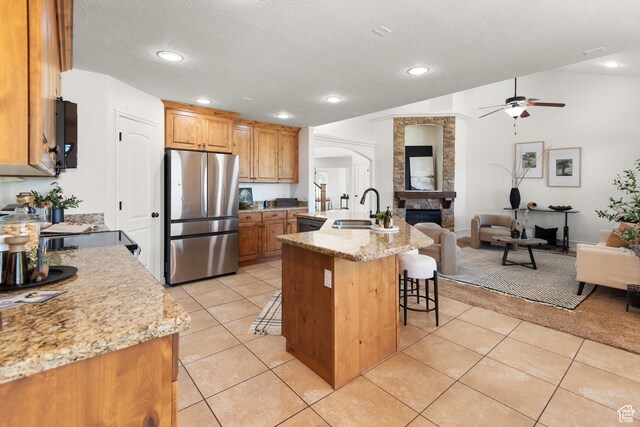 15337 S Eagle Crest Dr E, Draper, UT 84020 - kitchen featuring freestanding refrigerator, open floor plan, ceiling fan, a kitchen bar, and arched walkways