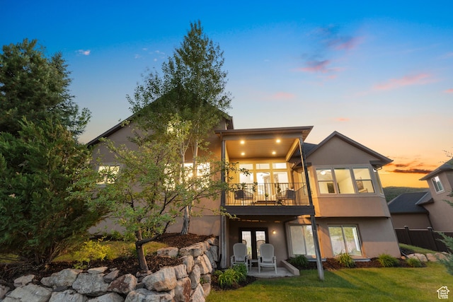 15337 S Eagle Crest Dr E, Draper, UT 84020 - back of property at dusk featuring stucco siding, a patio area, and a lawn