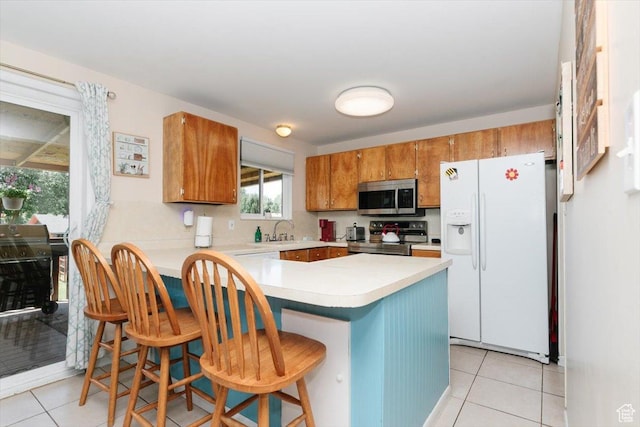 623 W 1635 N, Clinton, UT 84015 - kitchen with appliances with stainless steel finishes, light tile patterned floors, brown cabinets, a peninsula, and light countertops