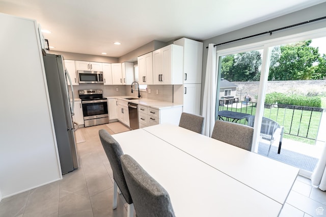2466 N 1050 W, Clinton, UT 84015 - kitchen featuring appliances with stainless steel finishes, light tile patterned flooring, backsplash, light countertops, and white cabinetry