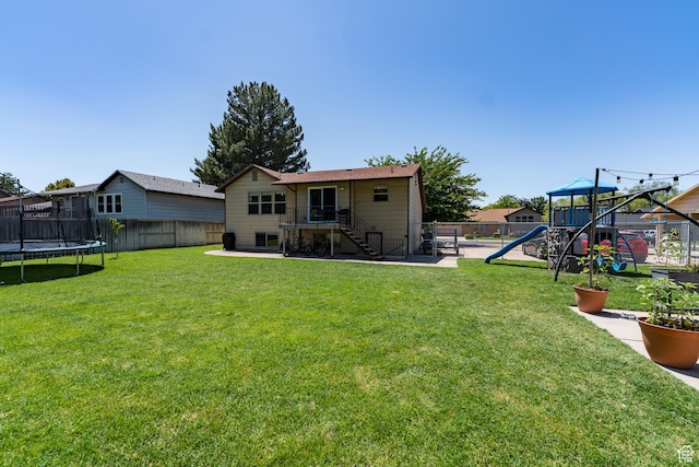 2466 N 1050 W, Clinton, UT 84015 - rear view of house with a playground, a trampoline, a fenced backyard, stairs, and a patio area