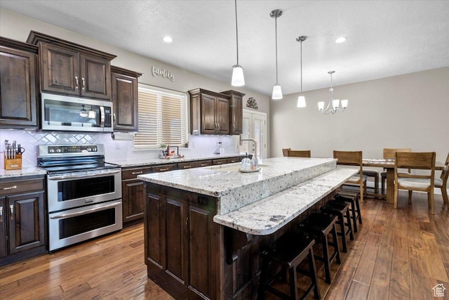 216 E 1370 S, Nephi, UT 84648 - kitchen with appliances with stainless steel finishes, a chandelier, a breakfast bar area, a kitchen island with sink, and dark brown cabinetry