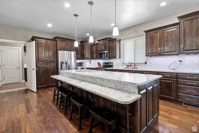 216 E 1370 S, Nephi, UT 84648 - kitchen featuring appliances with stainless steel finishes, dark wood finished floors, a kitchen breakfast bar, a kitchen island with sink, and recessed lighting