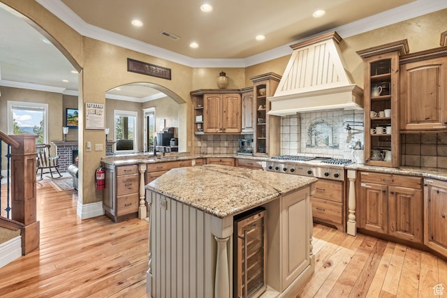 364 N Tanner Ln, Midway, UT 84049 - kitchen featuring beverage cooler, stainless steel gas cooktop, custom range hood, a center island, and light wood-type flooring