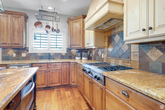 916 Ledgestone Ln, Heber City, UT 84032 - kitchen with stainless steel gas cooktop, premium range hood, light wood-type flooring, backsplash, and light stone counters