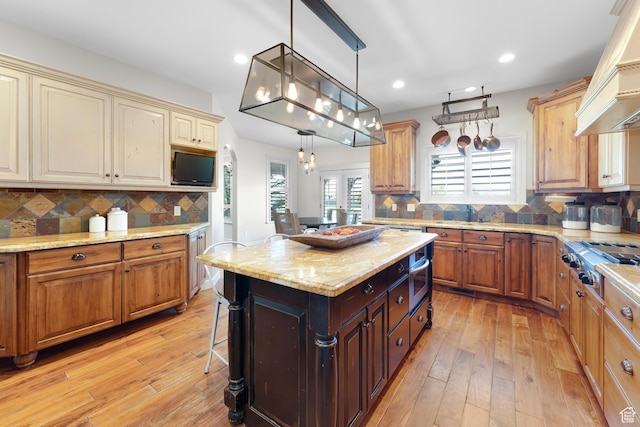 916 Ledgestone Ln, Heber City, UT 84032 - kitchen with stainless steel gas stovetop, light wood-style flooring, backsplash, recessed lighting, and a kitchen breakfast bar