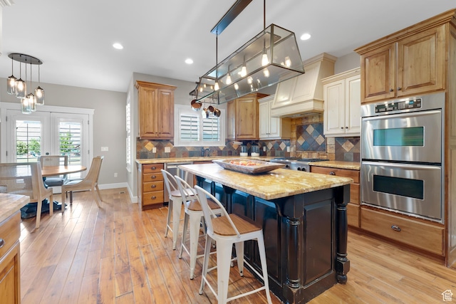 916 Ledgestone Ln, Heber City, UT 84032 - kitchen with stainless steel appliances, tasteful backsplash, light wood-style floors, a center island, and light stone counters